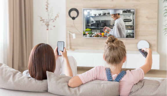 two girls watching a cooking show on tv using an antenna