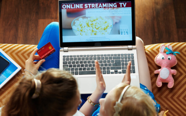 mother and child watching online streaming tv with a laptop on the couch