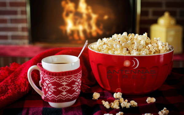 Cozy fireplace with a hot chocolate and bowl of popcorn, Antennas Direct logo