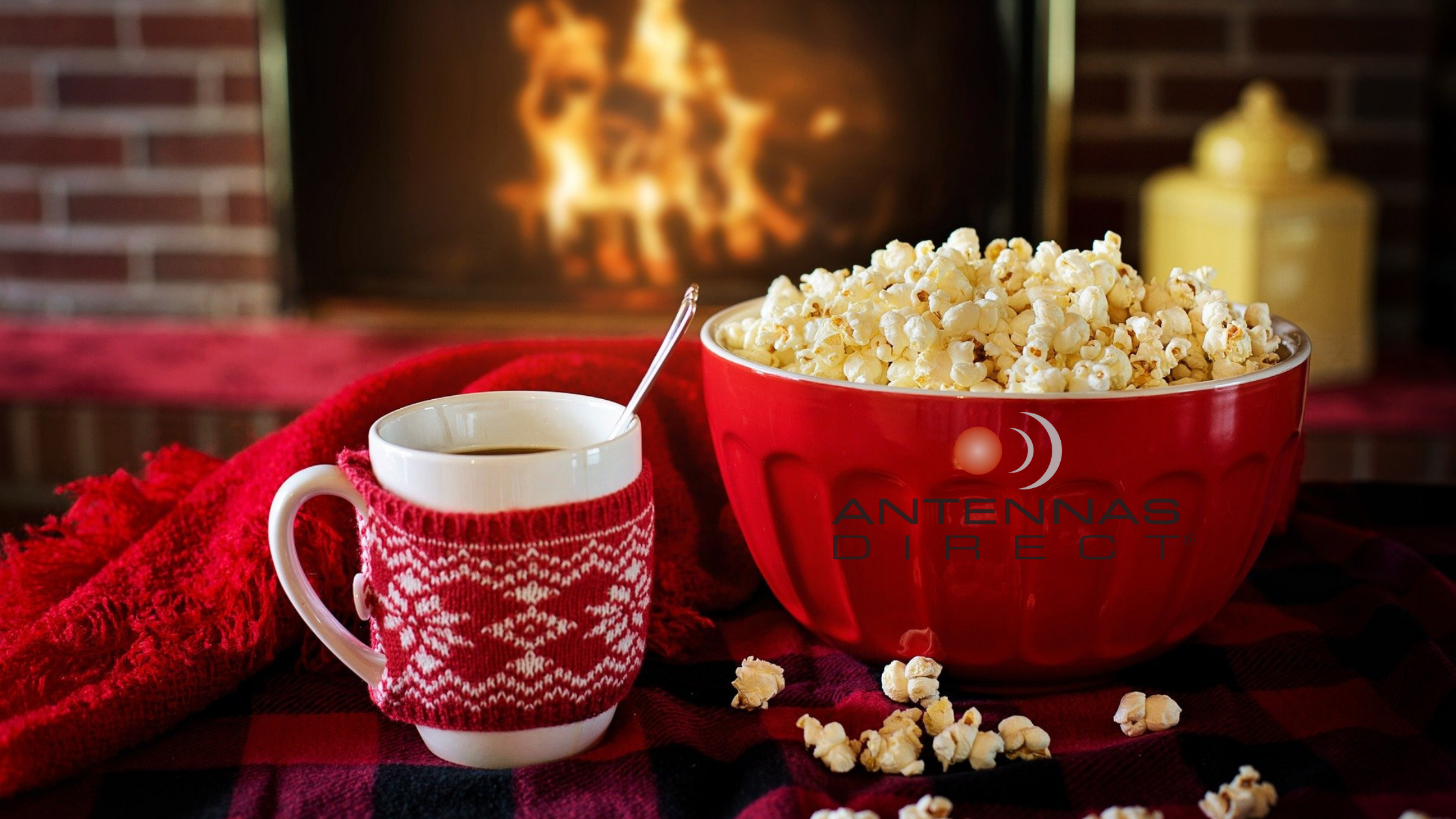 Cozy fireplace with a hot chocolate and bowl of popcorn, Antennas Direct logo